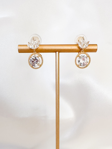Crystalized white stone clip-on earrings shaped as a crown with a charming circle dangling below.