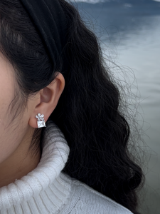 silver & white cubic zirconia shaped into a flower atop a square gem clipon earrings on model