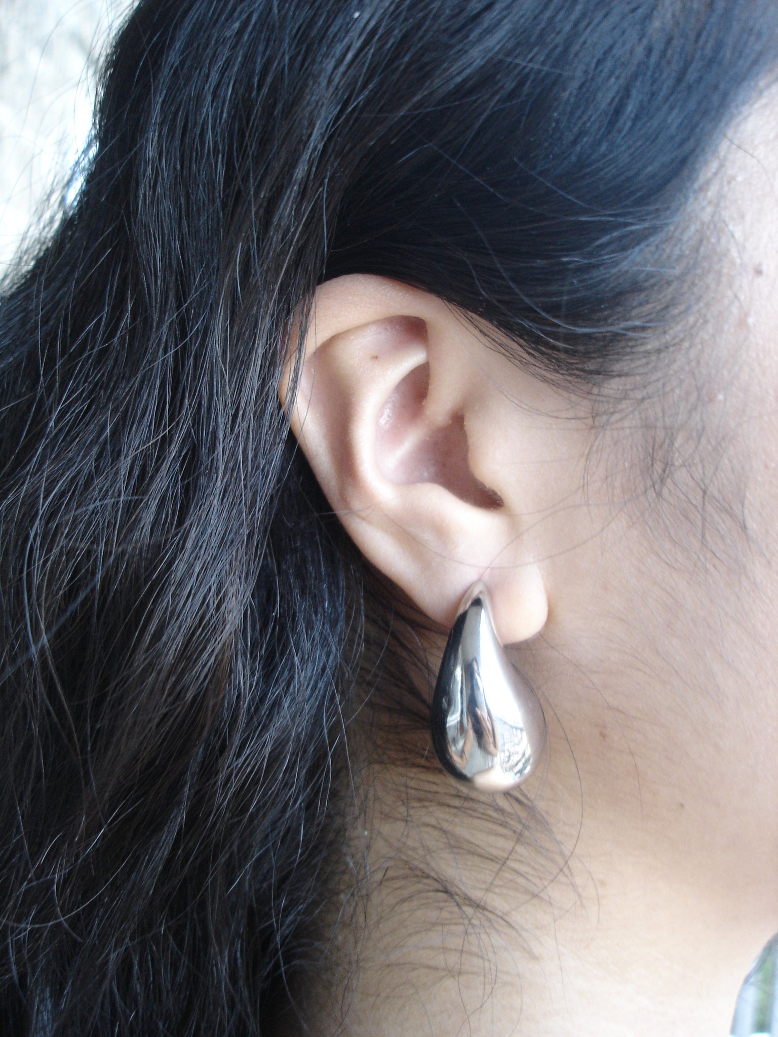 Close-up of an ear with a silver earring, hair partially covering the face.