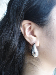 Close-up of an ear with a silver earring, hair partially covering the face.