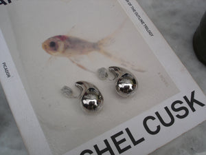 Silver earrings on a book titled 'Shel Cusk' with a fish illustration.
