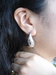Close-up of an ear with a silver earring being adjusted.