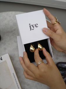 Gold rings being held above a 'iyc' branded card on a neutral background