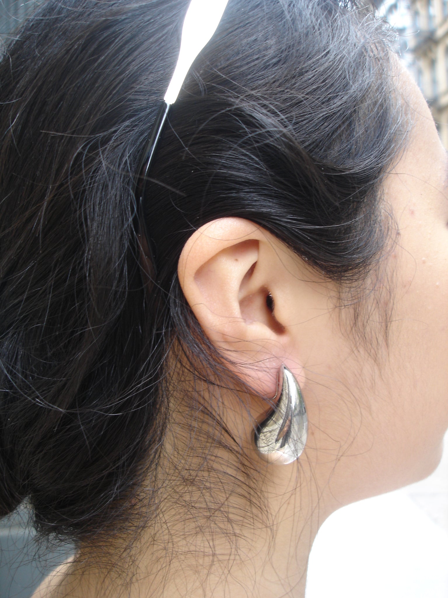 Close-up of an ear with a silver earring, hair partially covering the face.
