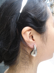 Close-up of an ear with a silver earring, hair partially covering the face.