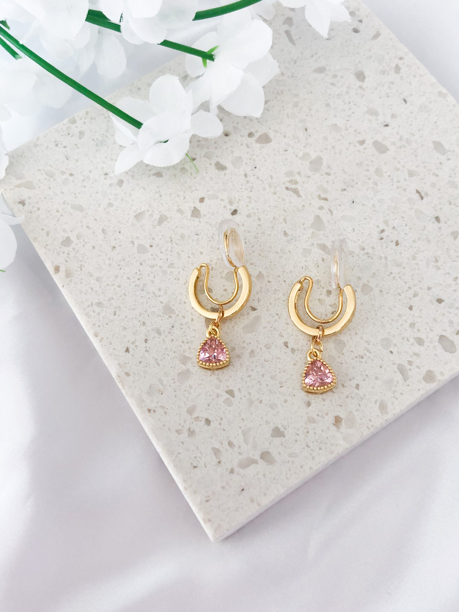 small gold clip-on hoop earrings with pink triangle charm