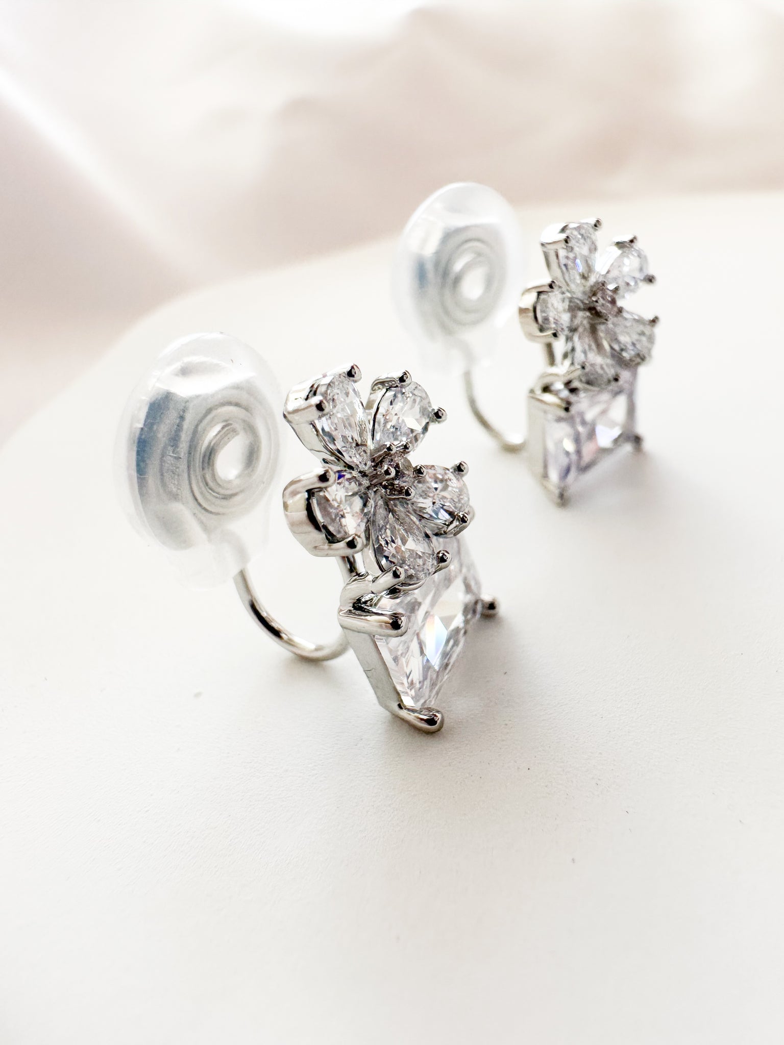 silver & white cubic zirconia shaped into a flower atop a square gem clipon earrings
