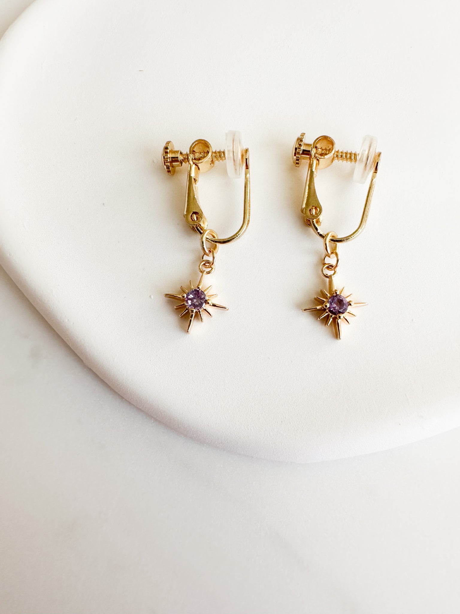 gold screwback clipon earrings with gold constellation charm with dark purple circle gem in middle