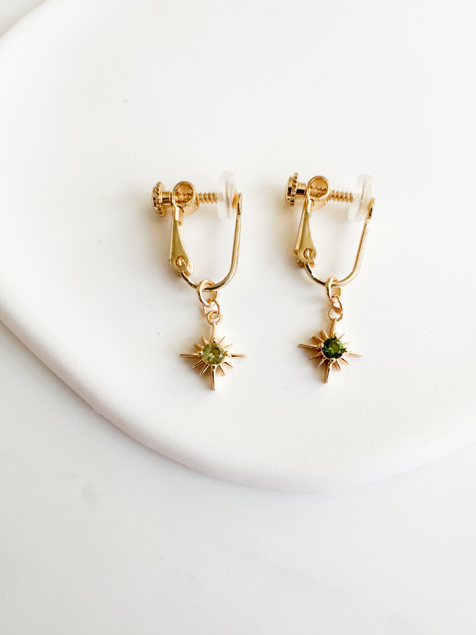 gold screwback clipon earrings with gold constellation charm with dark green circle gem in middle