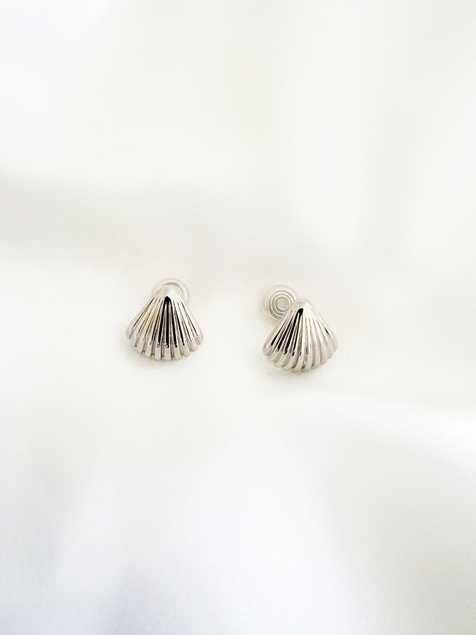 Silver shell-shaped earrings on a white background