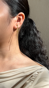 A pair of gold-colored threader dangle earrings on model