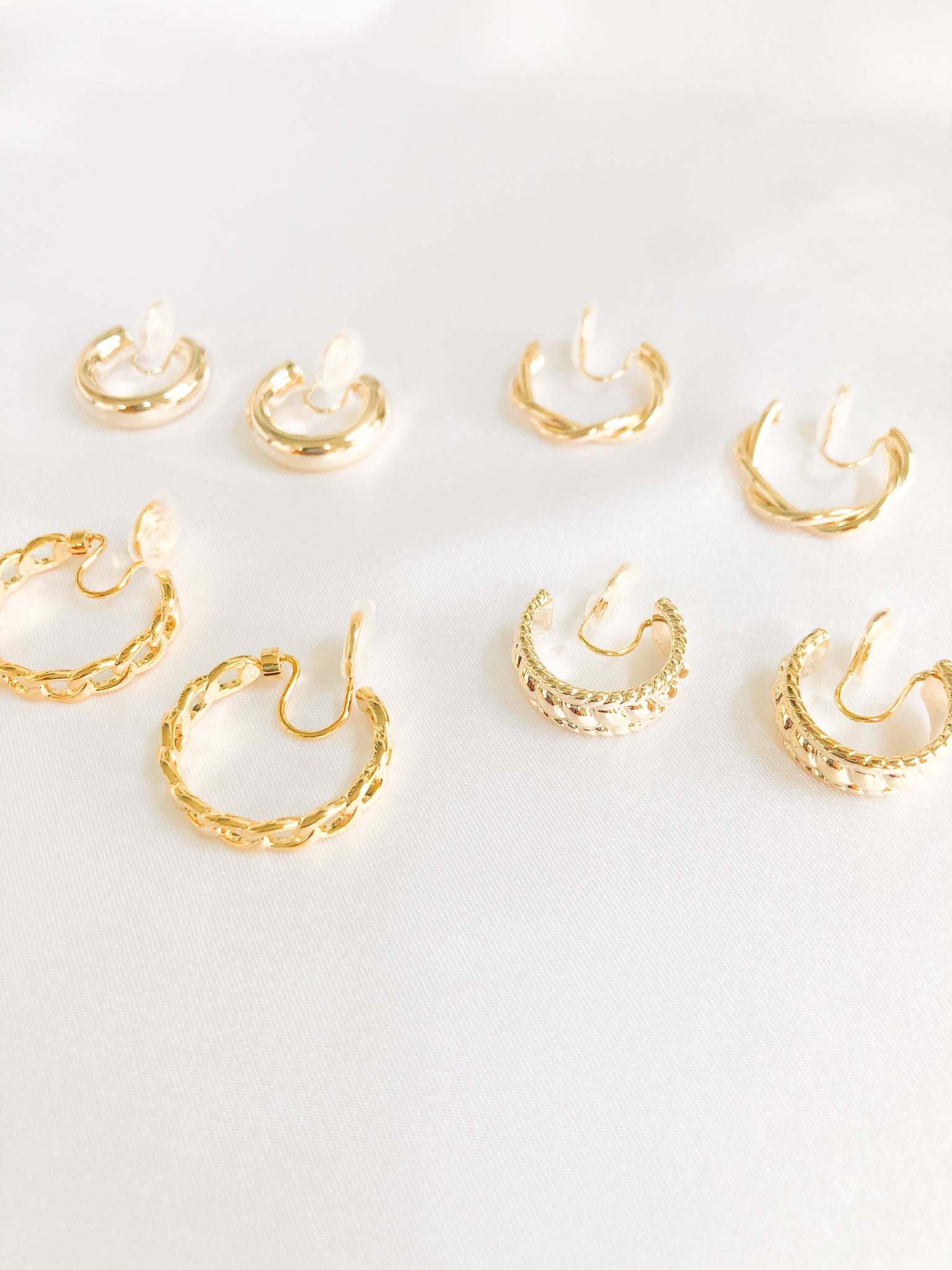Add some glam to your wardrobe with our bundle of different gold clip-on hoop earrings. This set features four pairs of earrings, each with a unique design. Amy Clip-on Hoops, Twisted Clip-on Hoops, Ella Clip-on Hoops, and Jessika Clip-on Hoops